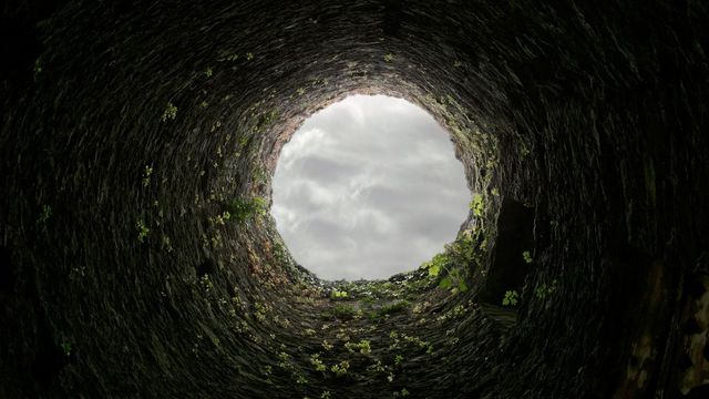 Looking through a well, up at the sky. 
