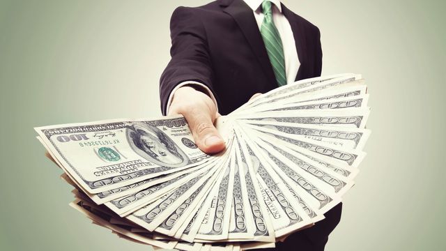Businessman holding a fan of money.