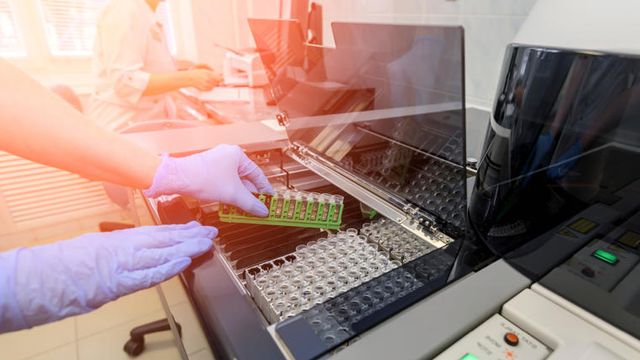 Hands of a female laboratory assistant loading a liquid sample for chemical analysis. 