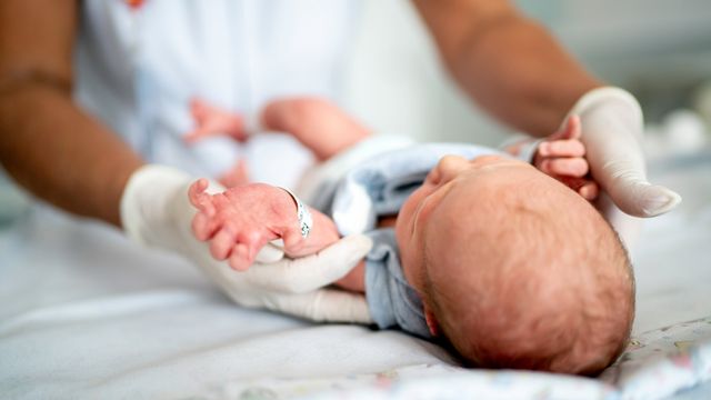 Medical professional gently handling a newborn baby, representing infant care and SIDS awareness. 