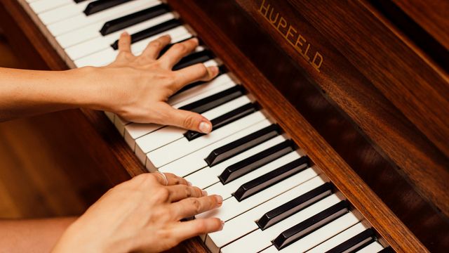 A person's hands rest on piano keys, poised to play. 