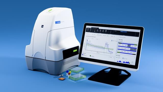Laboratory DNA analysis machine next to a computer monitor displaying scientific data graphs and results. 