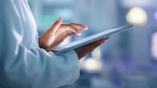 A lab technician using a digital tablet in a modern paperless laboratory environment. 