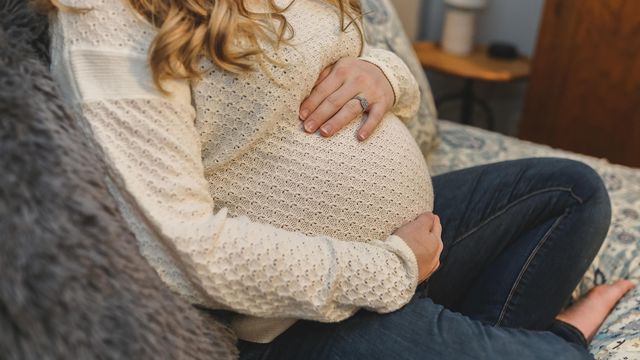 Pregnant woman holding her belly, illustrating vaccination risk to pregnant women and baby. 